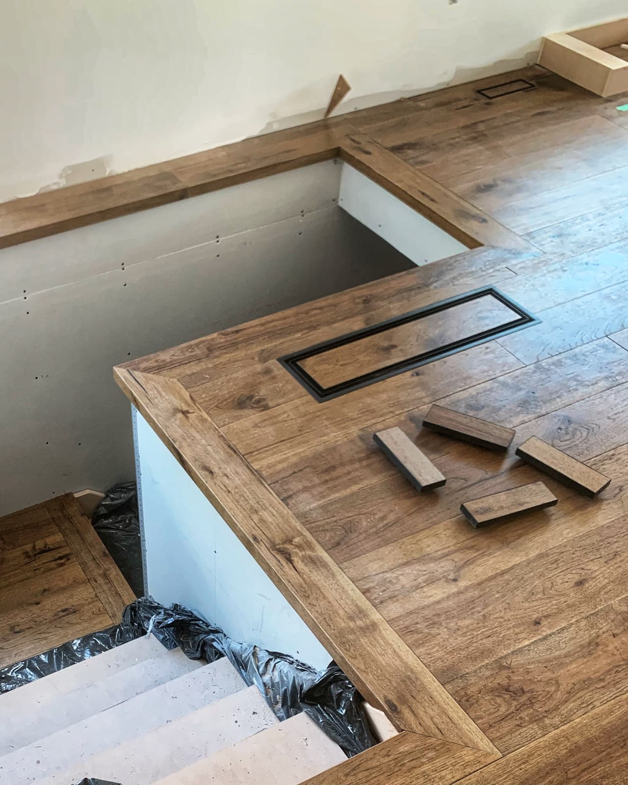 A custom floor vent inset into a hardwood floor within a picture-frame border