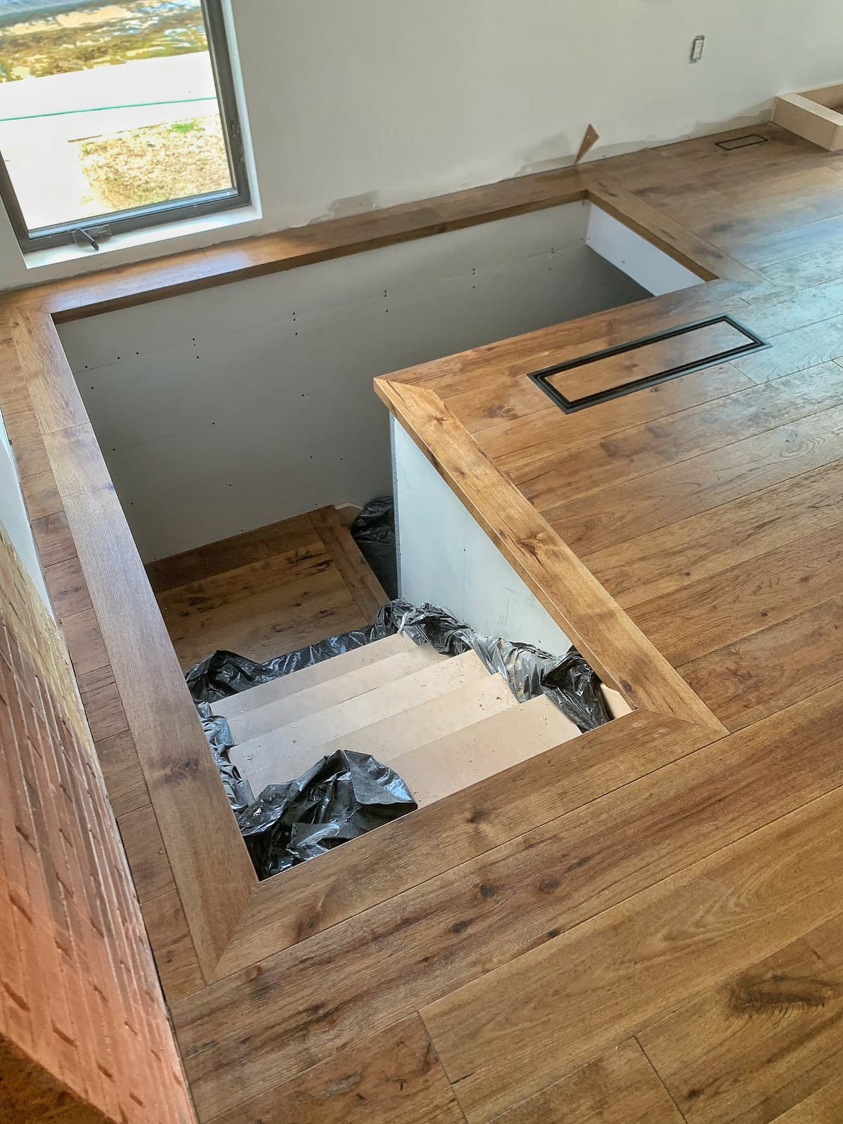 Corner detail of a hardwood floor with a picture-frame border and an integrated custom vent