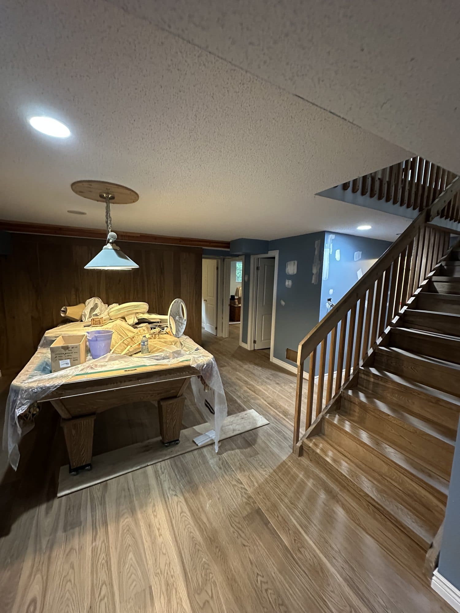 The same basement finished with warm wood floors and a wood-panelled wall