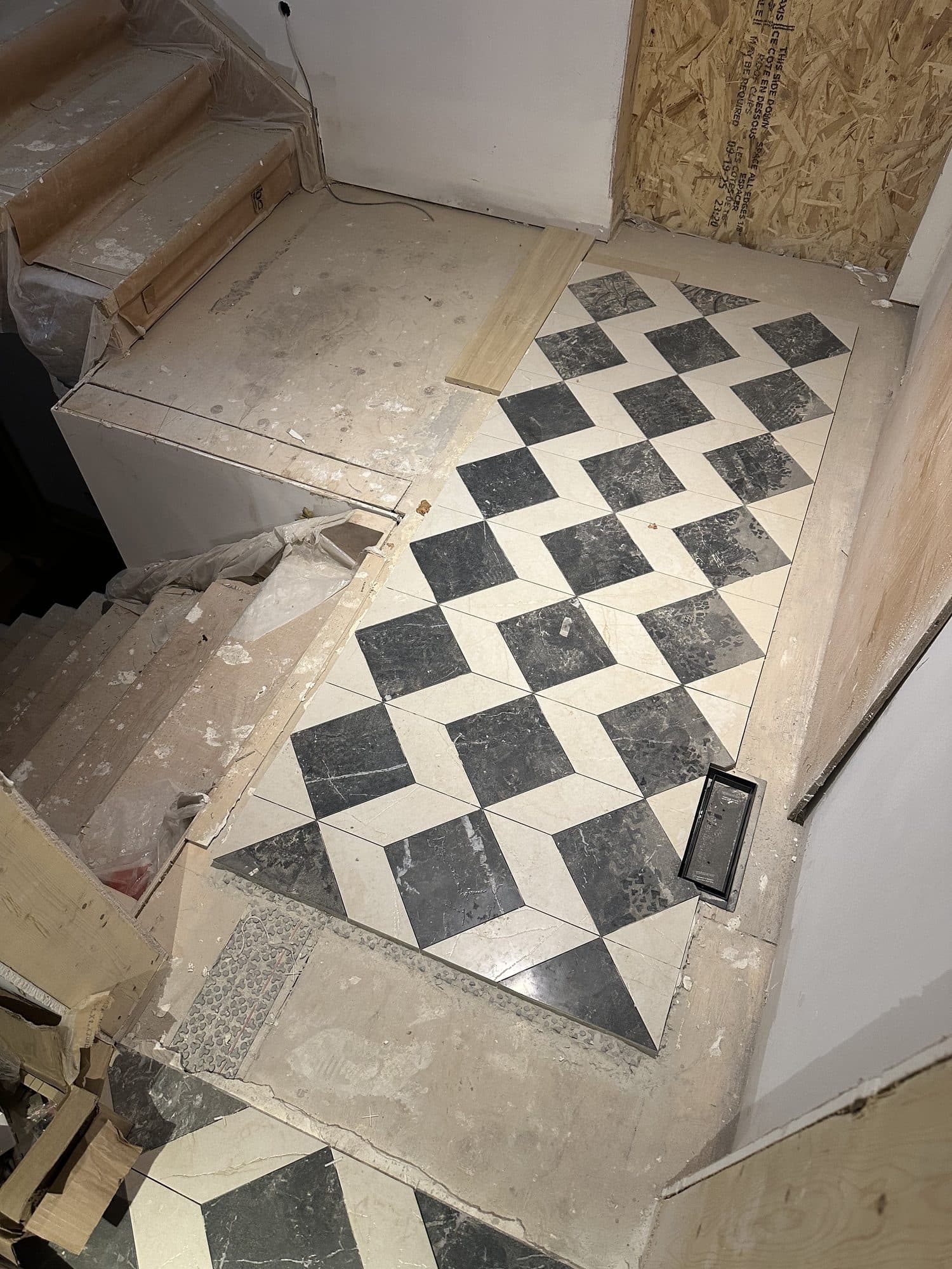 A patterned tile landing with unfinished surrounding floor