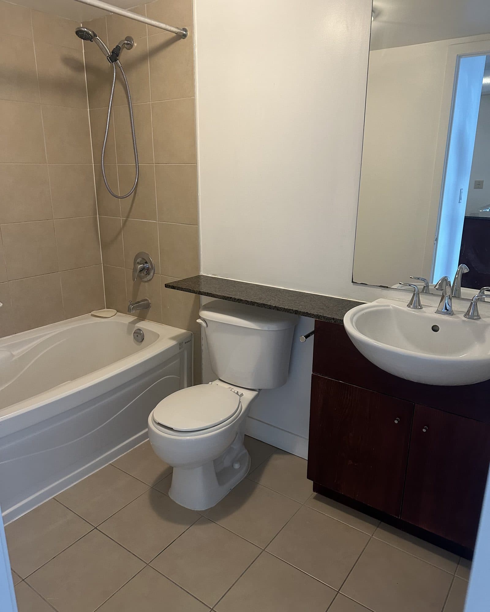 A dated bathroom with a dark vanity and beige tile before renovation