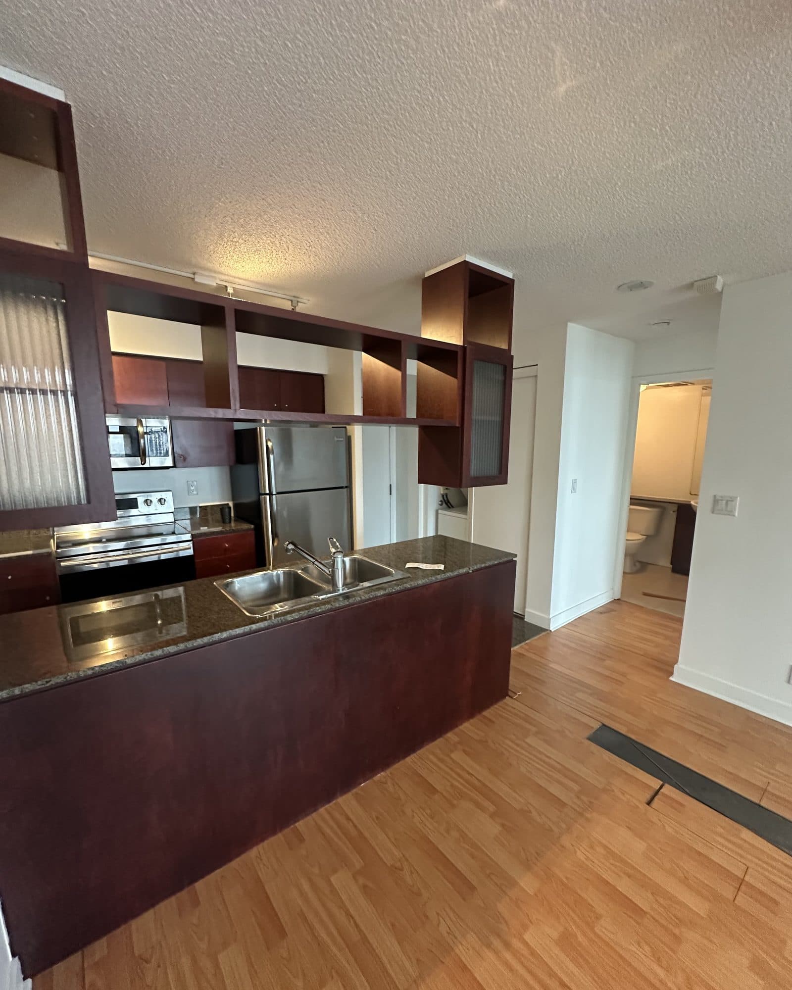 A dated kitchen with dark cherry cabinets and granite before renovation