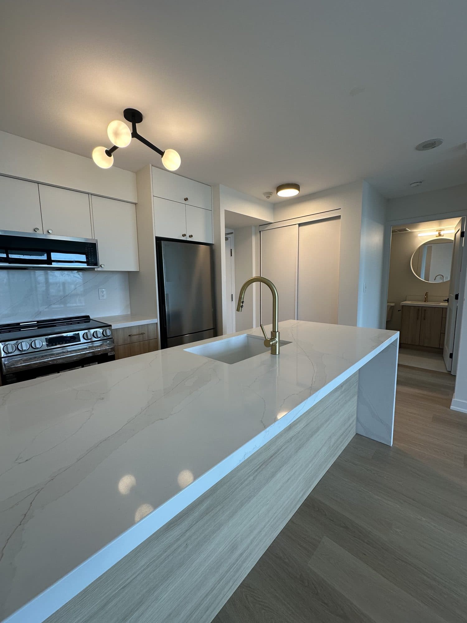 The same kitchen renewed with white cabinetry and a waterfall quartz island