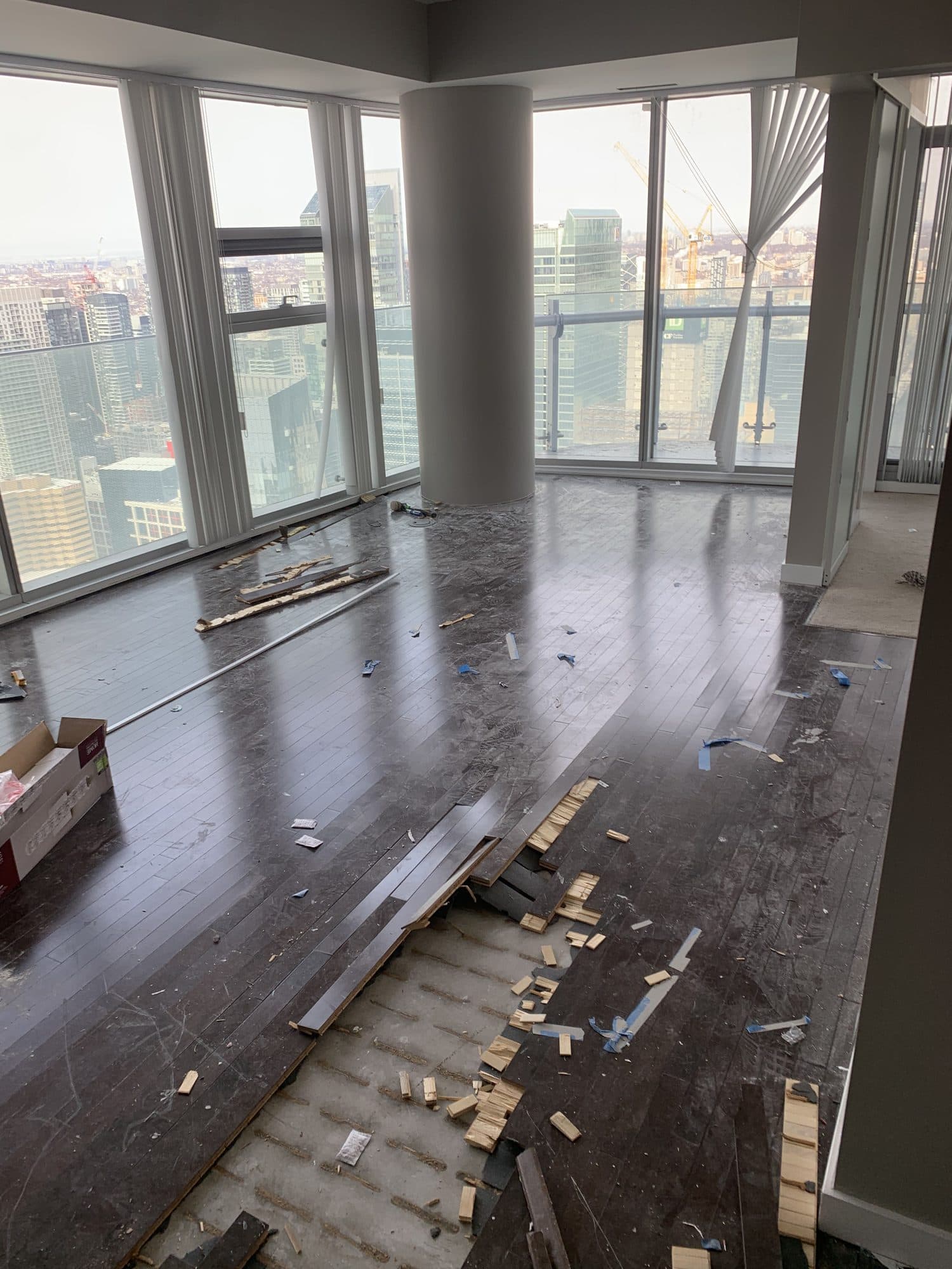 A bare condo subfloor with a corner window before new flooring