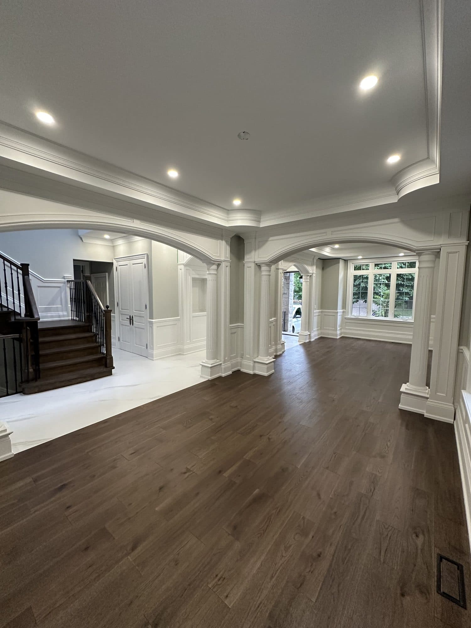 An open interior with arched openings, columns and wide dark hardwood flooring