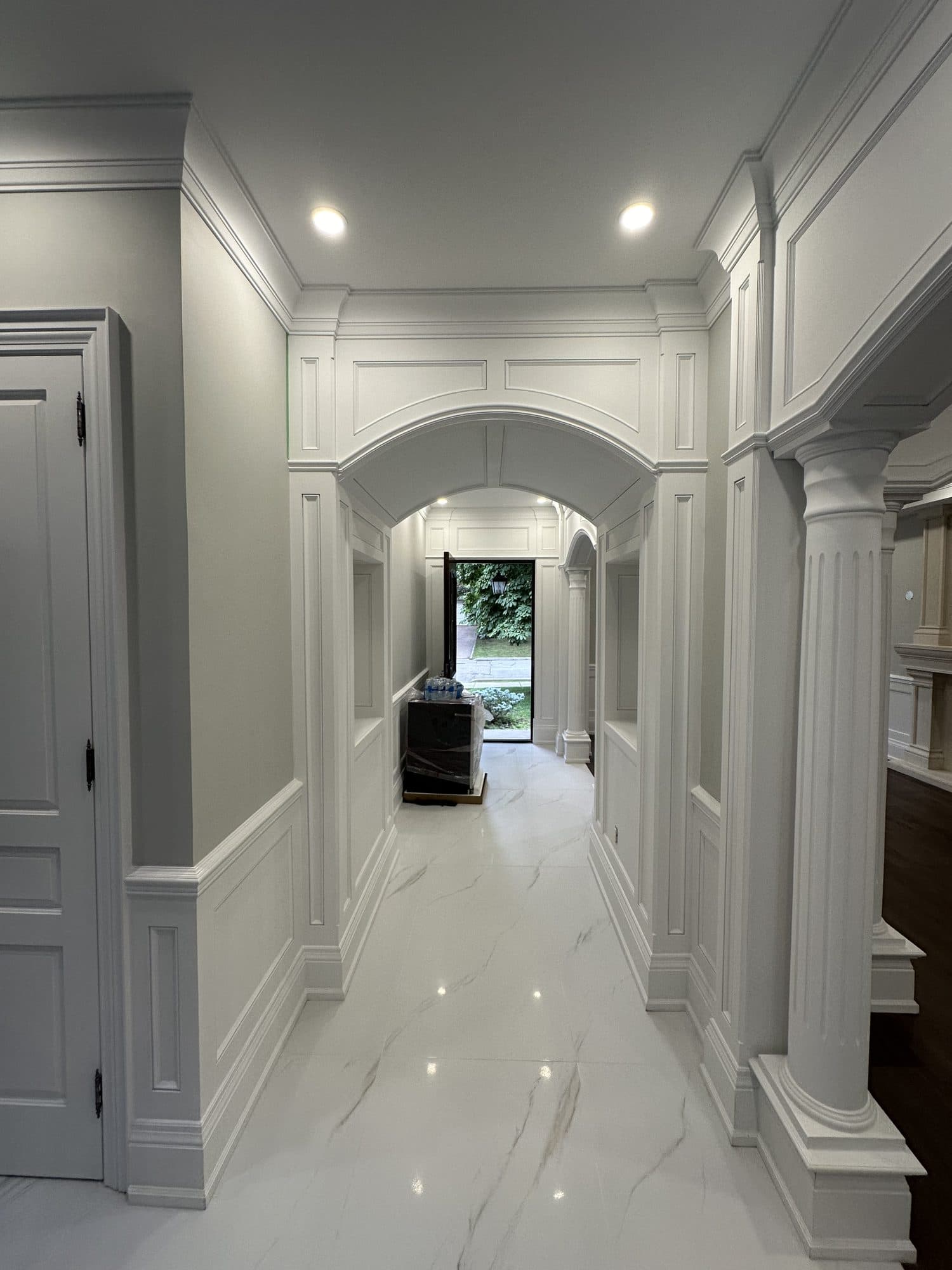 A panelled hallway with arched passages, columns and a marble floor