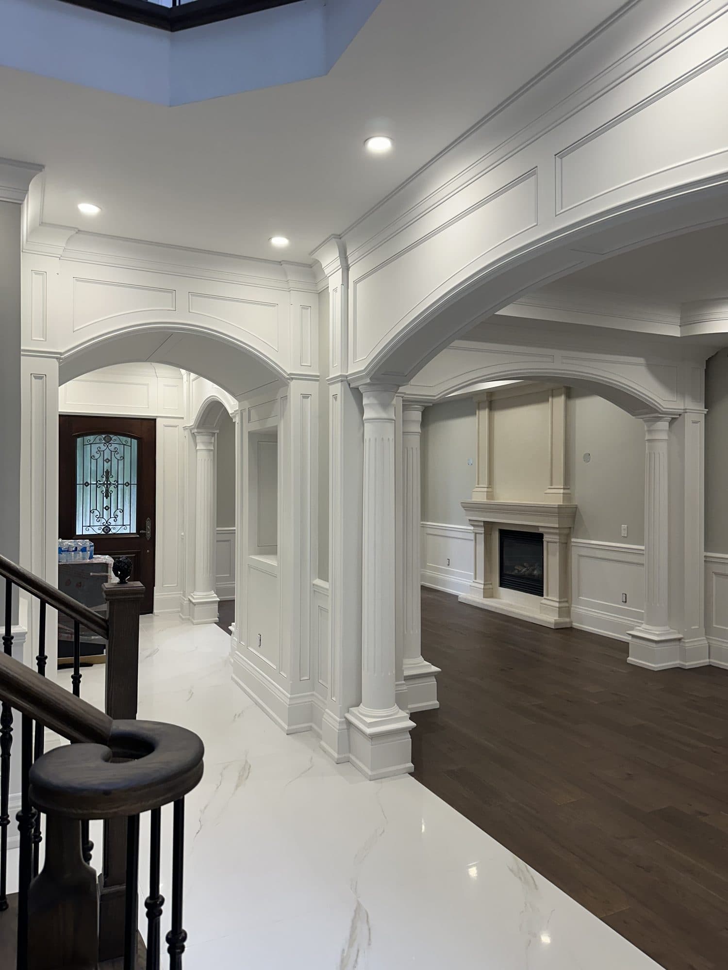 A grand foyer with fluted columns, arched openings and a carved stone fireplace