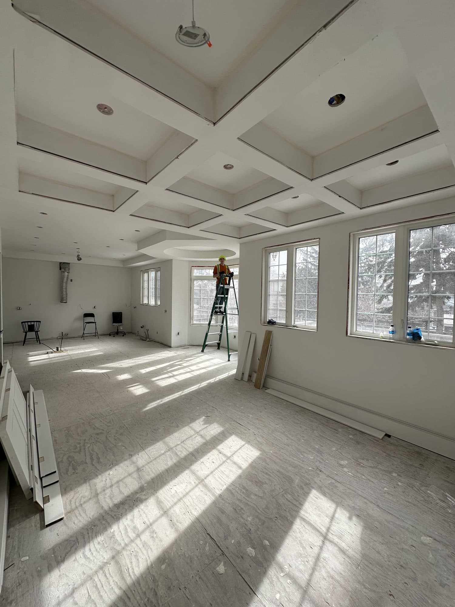A coffered ceiling under construction above a room prepared for flooring