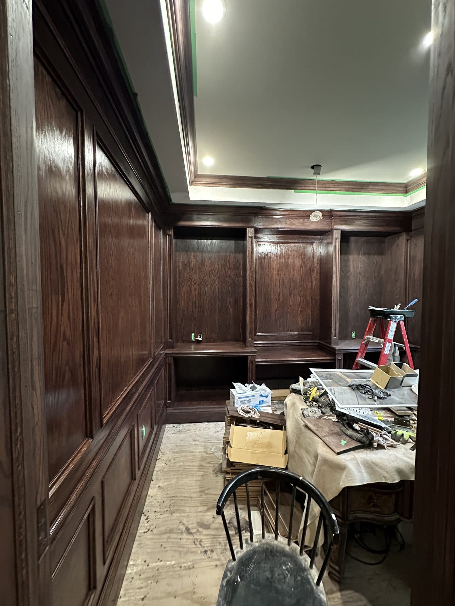A study finished in dark walnut panelling beneath a coffered ceiling