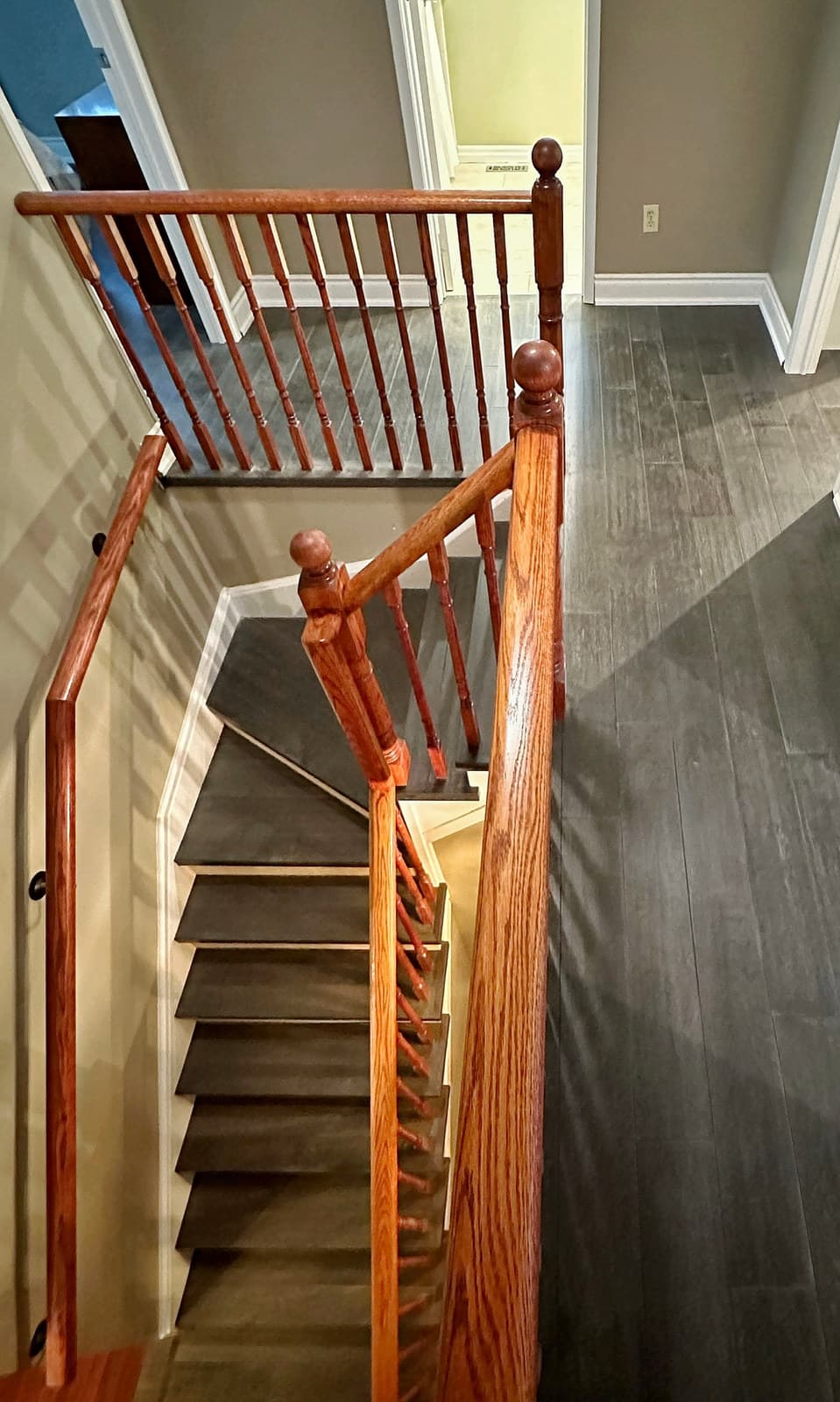 An oak staircase seen from the upper landing with new hardwood flooring