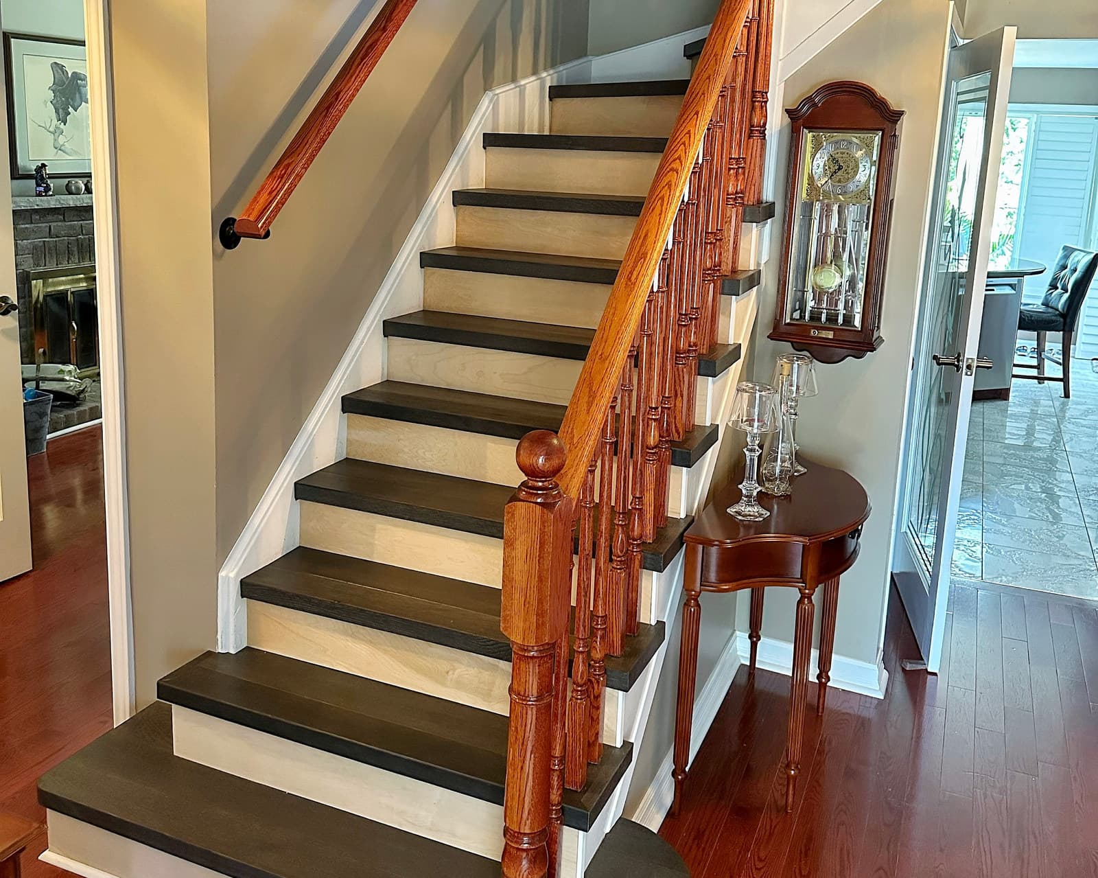 An oak staircase with dark treads leading past a hallway toward a dining room