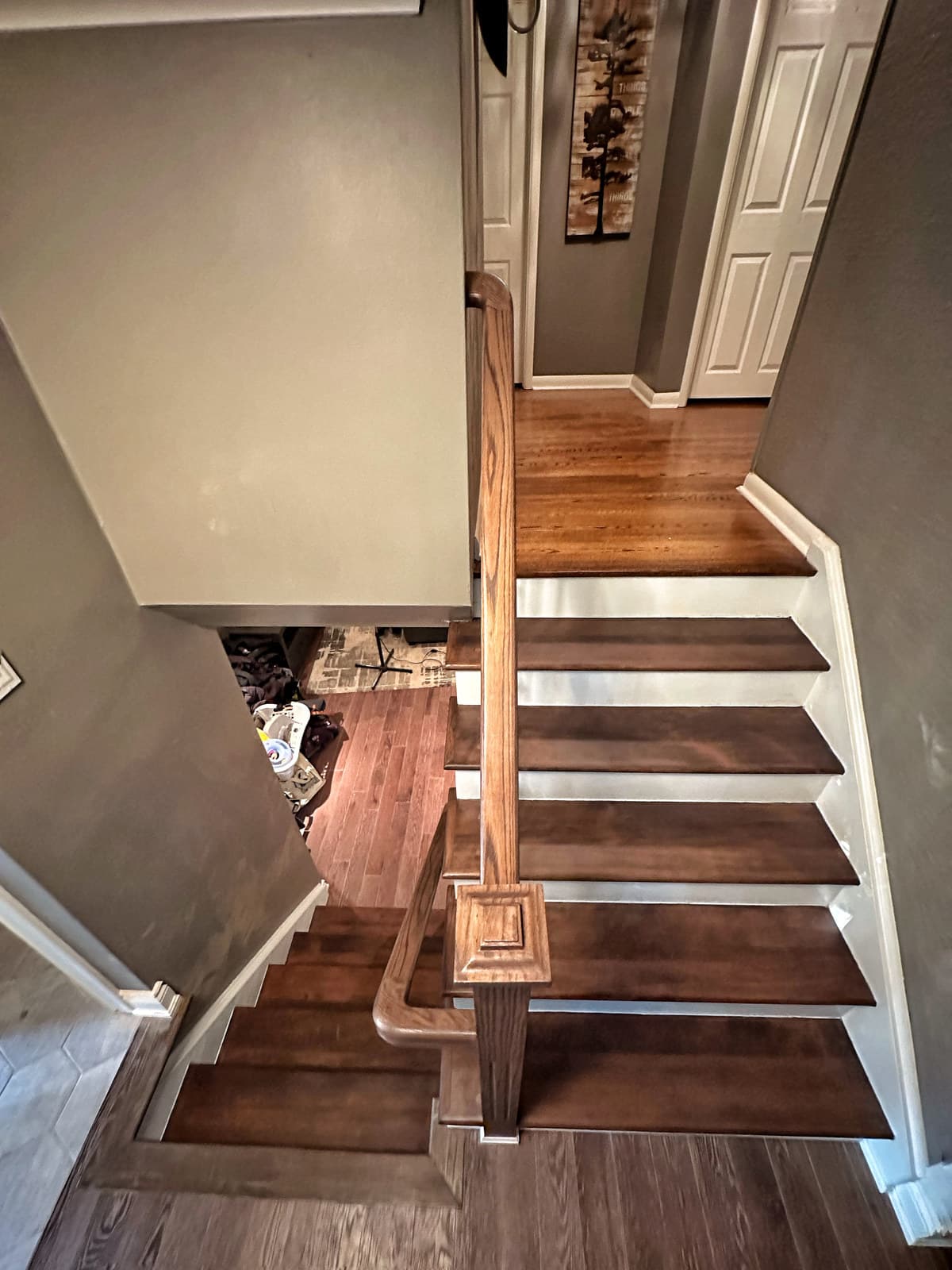 A white and dark-oak staircase in a bright hallway with hardwood flooring