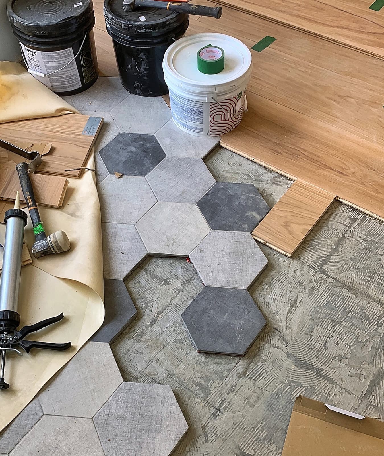 Hexagonal floor tile meeting hardwood flooring during installation