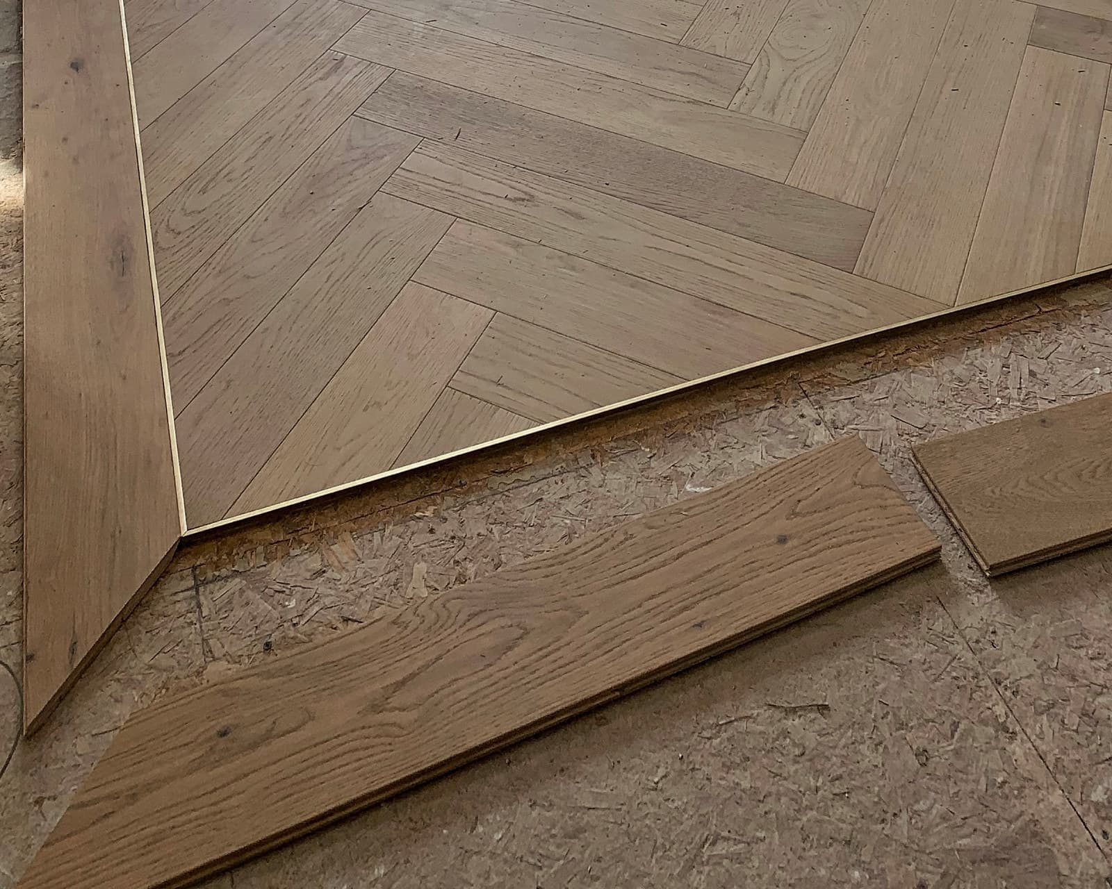 A mitred border framing a herringbone hardwood floor