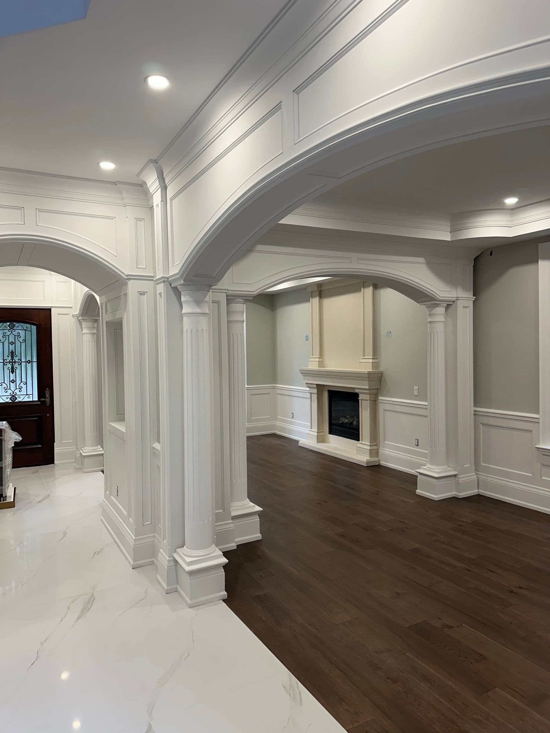 A formal room with an arched entry, fireplace, coffered ceiling and dark hardwood floors