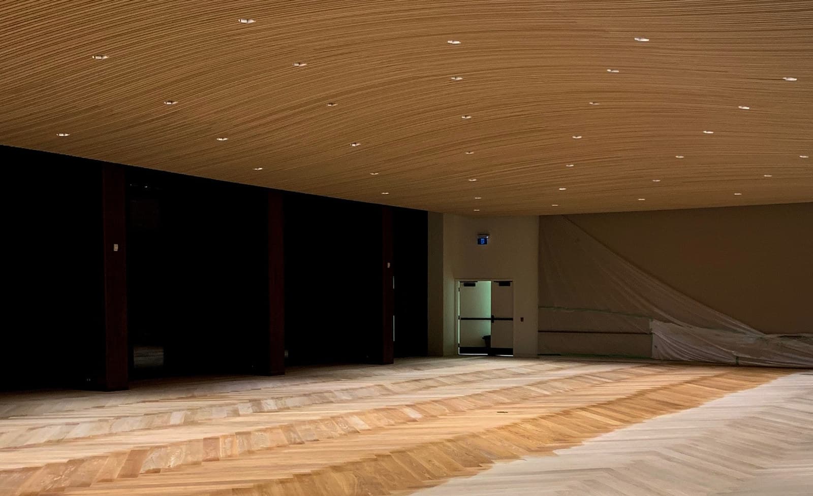 Custom herringbone flooring beneath a curved wood-slat ceiling at the Toronto Congress Centre