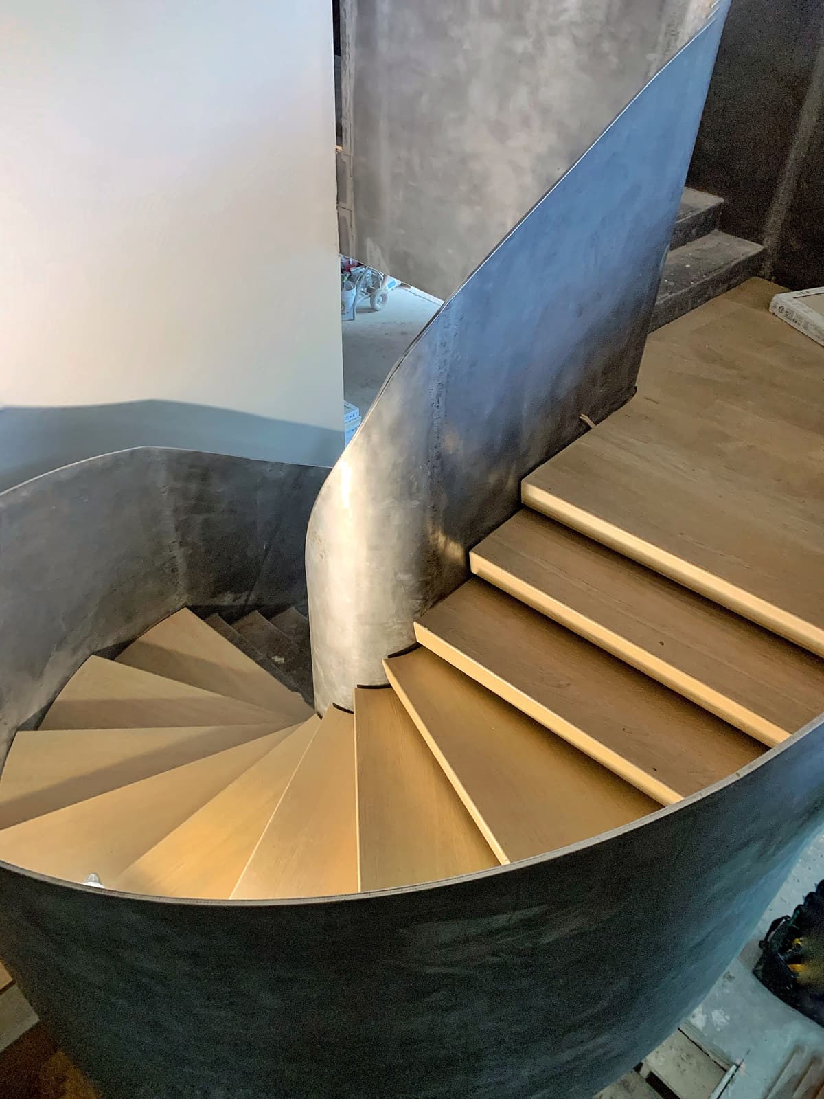 A curved staircase with wood treads and a sculptural form